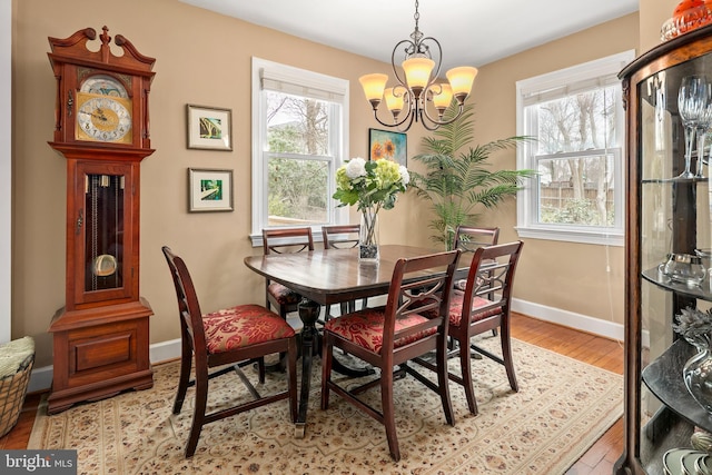 dining space with a notable chandelier, plenty of natural light, baseboards, and light wood-type flooring