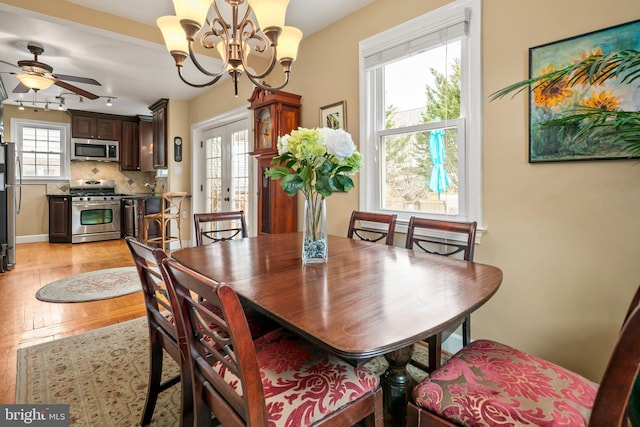 dining room featuring french doors, light wood-style flooring, and ceiling fan with notable chandelier