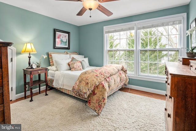 bedroom with multiple windows, wood finished floors, and baseboards