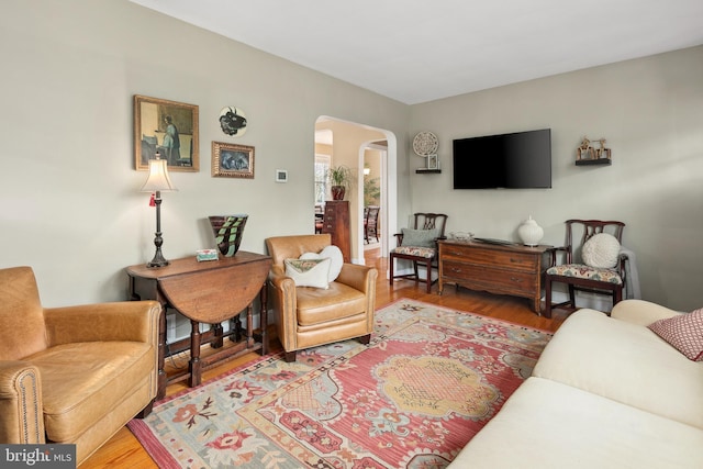 living room with arched walkways and wood finished floors