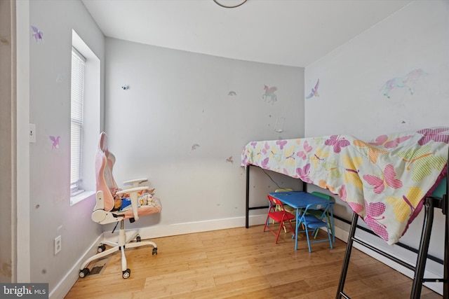 bedroom with baseboards, multiple windows, and wood finished floors