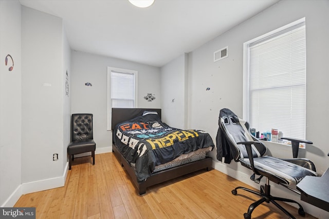 bedroom featuring light wood finished floors, visible vents, and baseboards