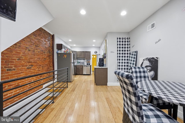 kitchen featuring brick wall, light countertops, recessed lighting, light wood-style floors, and stainless steel appliances