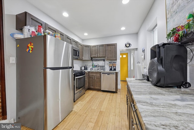 kitchen featuring light wood-style flooring, recessed lighting, a sink, light countertops, and appliances with stainless steel finishes