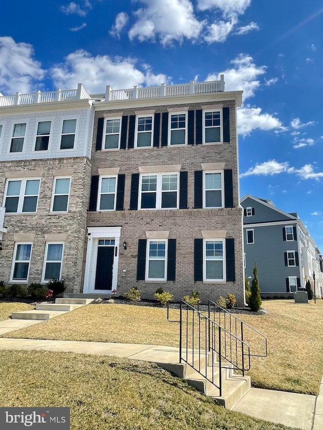 multi unit property with a front yard and brick siding