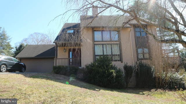 view of front facade featuring a front yard, an attached garage, a shingled roof, a chimney, and stucco siding