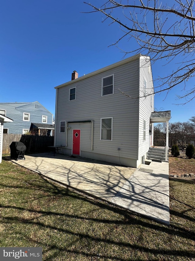 rear view of house featuring a yard, a chimney, a patio, and fence