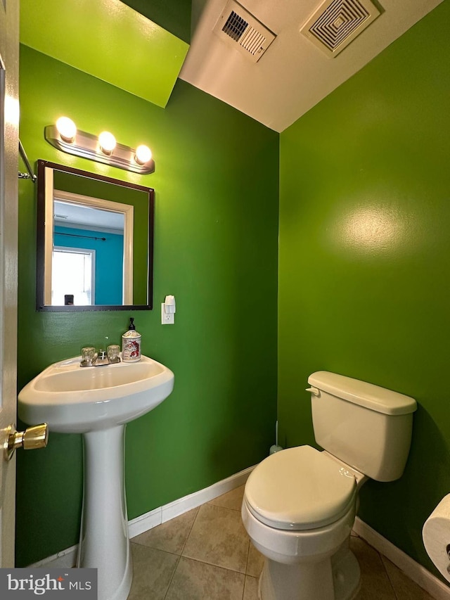 half bath with tile patterned floors, visible vents, toilet, and baseboards