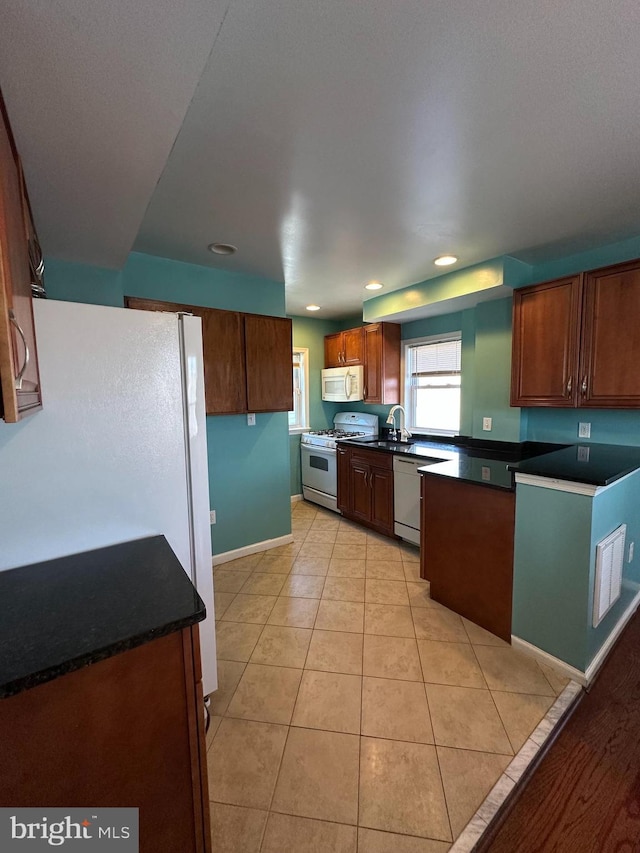 kitchen featuring dark countertops, baseboards, light tile patterned floors, recessed lighting, and white appliances