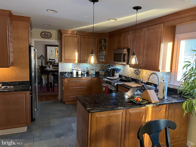 kitchen featuring brown cabinets, decorative backsplash, stainless steel appliances, a peninsula, and glass insert cabinets