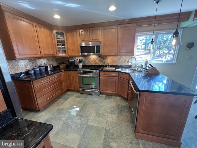 kitchen featuring a sink, brown cabinets, appliances with stainless steel finishes, and a peninsula