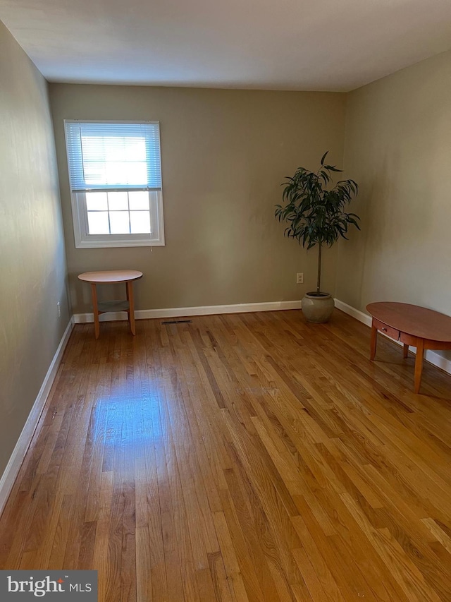 empty room with baseboards and hardwood / wood-style floors