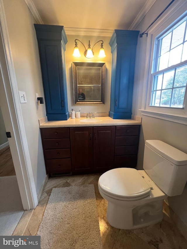 bathroom featuring vanity, toilet, crown molding, and baseboards