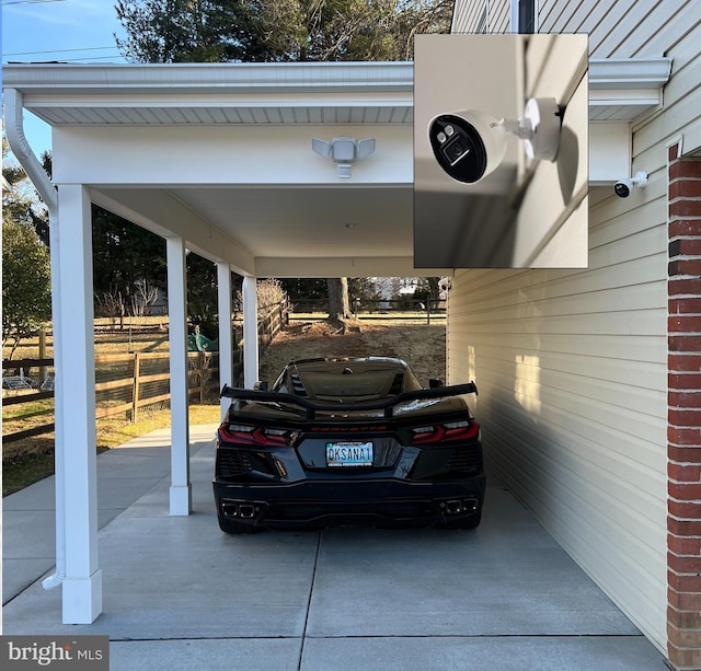 view of vehicle parking with concrete driveway and fence