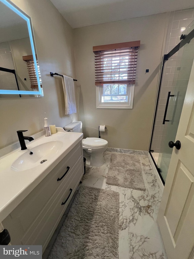 bathroom featuring marble finish floor, a stall shower, vanity, and toilet