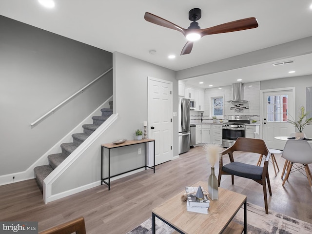 living area featuring visible vents, baseboards, stairway, recessed lighting, and light wood-style flooring