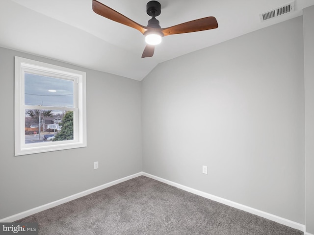 carpeted spare room featuring visible vents, baseboards, and vaulted ceiling