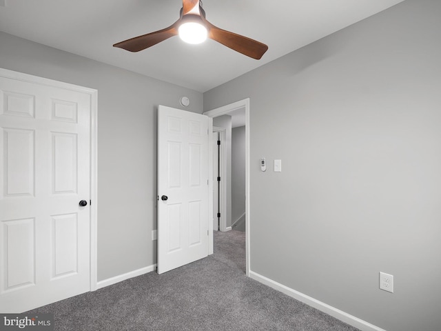 unfurnished bedroom with dark colored carpet, baseboards, and a ceiling fan