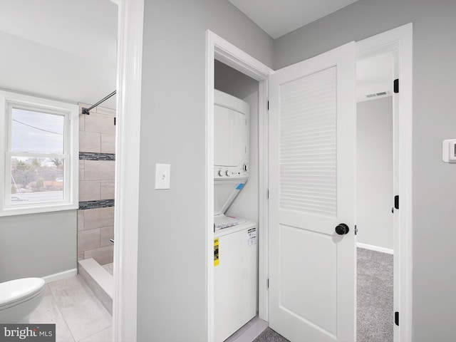 laundry room with visible vents, stacked washer and clothes dryer, laundry area, and baseboards