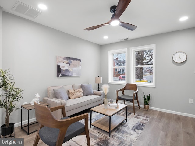 living area featuring baseboards, light wood-style floors, visible vents, and ceiling fan