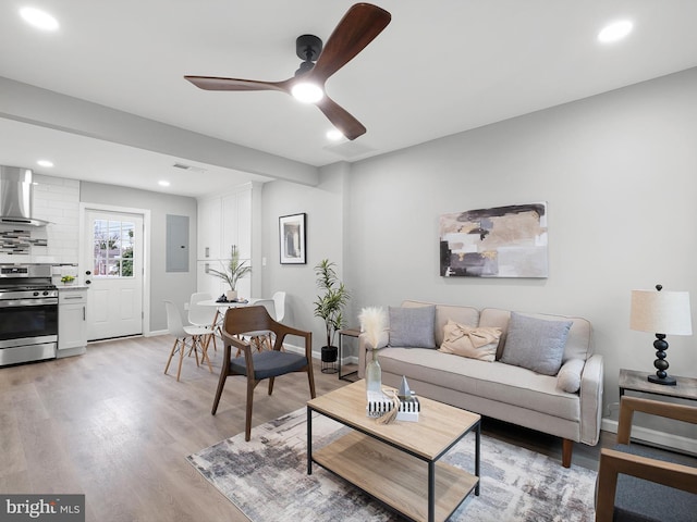 living area featuring baseboards, visible vents, electric panel, ceiling fan, and light wood-style floors