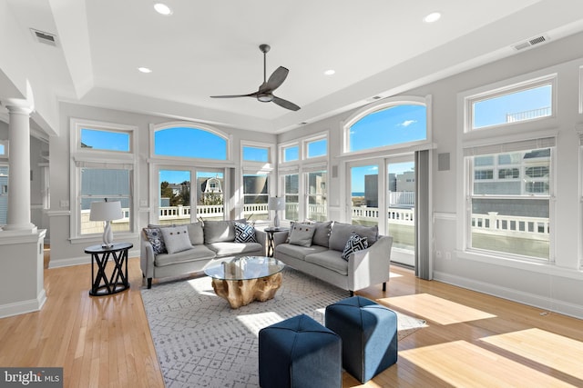 sunroom with visible vents, ceiling fan, a tray ceiling, and ornate columns