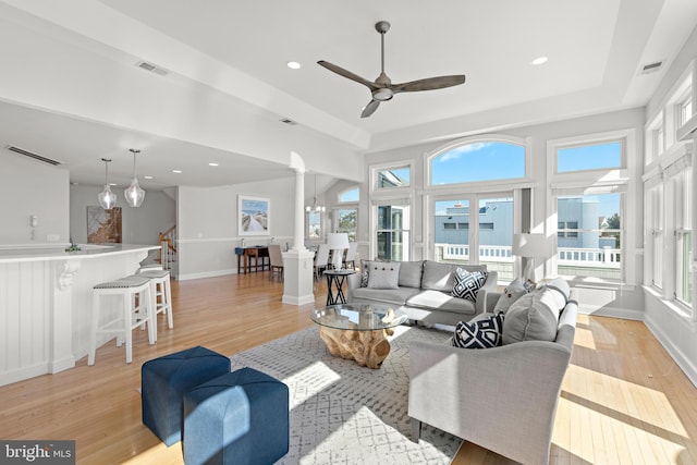 living room featuring visible vents, baseboards, light wood-style floors, and stairs