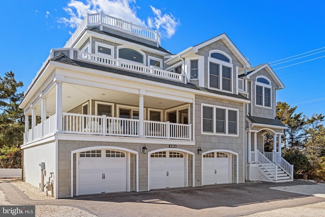 shingle-style home with decorative driveway and a garage