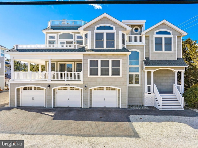 view of front of property with decorative driveway, a balcony, roof with shingles, and a garage