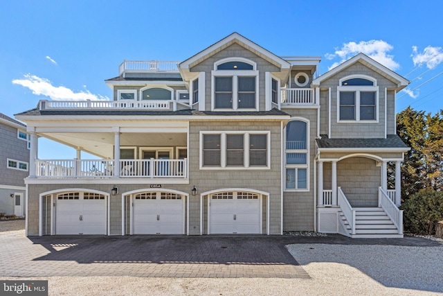 shingle-style home featuring a balcony, an attached garage, driveway, and a shingled roof