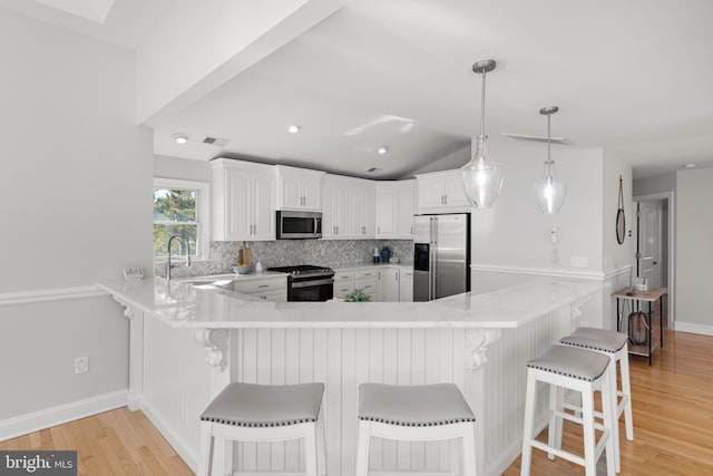 kitchen with tasteful backsplash, appliances with stainless steel finishes, a peninsula, and a sink