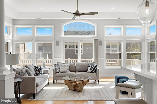 sunroom / solarium featuring plenty of natural light, ceiling fan, and decorative columns