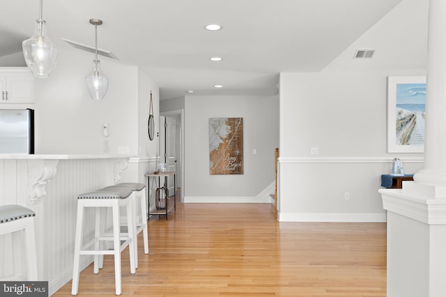 kitchen with visible vents, a breakfast bar, light wood-type flooring, recessed lighting, and freestanding refrigerator