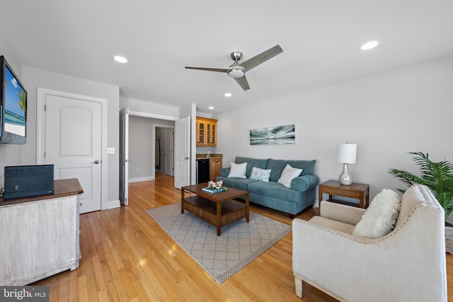 living area featuring baseboards, recessed lighting, ceiling fan, bar, and light wood-style floors