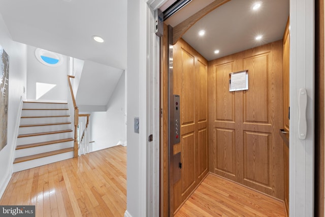 corridor with elevator, recessed lighting, light wood finished floors, and stairs