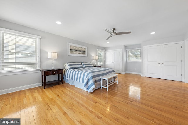 bedroom with recessed lighting, baseboards, two closets, and light wood-style flooring