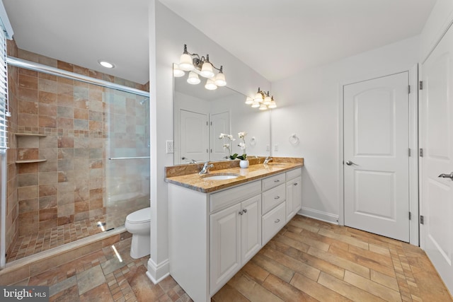 full bathroom featuring a sink, toilet, double vanity, and a shower stall