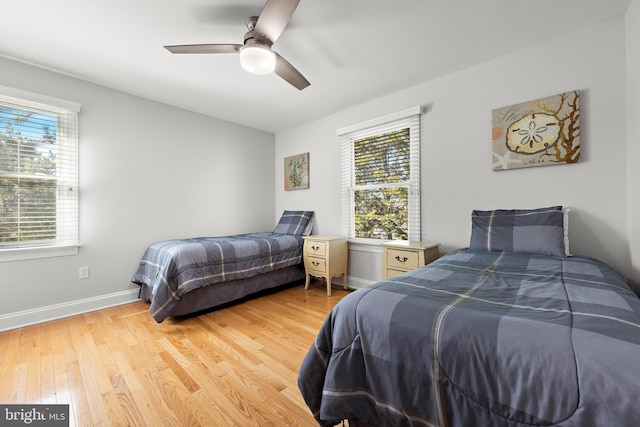 bedroom featuring light wood-type flooring, baseboards, and a ceiling fan