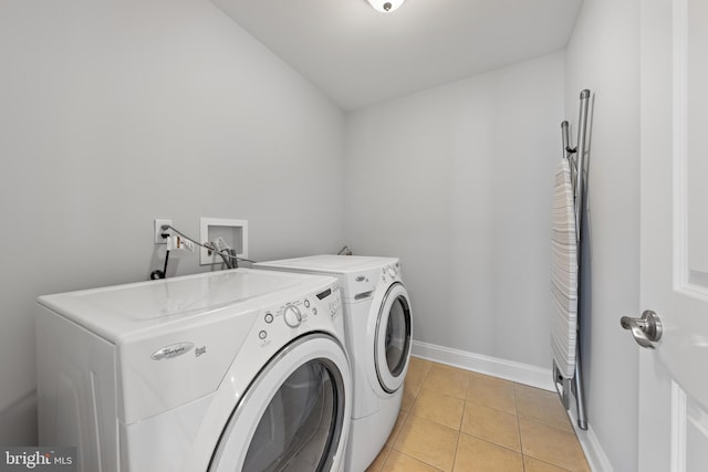 washroom featuring laundry area, light tile patterned floors, baseboards, and washing machine and clothes dryer