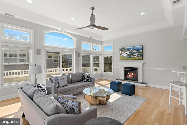 living room with visible vents, baseboards, a lit fireplace, and hardwood / wood-style floors