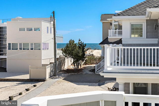 view of home's exterior featuring a shingled roof, a balcony, and fence