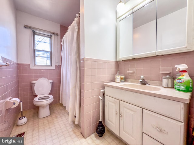 full bath with vanity, tile walls, toilet, and wainscoting