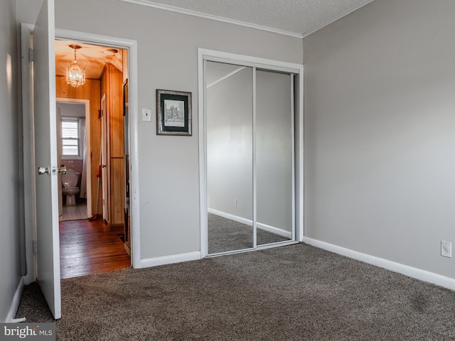 unfurnished bedroom featuring a closet, a textured ceiling, carpet, and an inviting chandelier