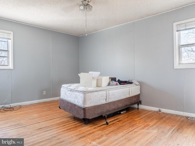 bedroom with a textured ceiling, light wood-type flooring, and ornamental molding