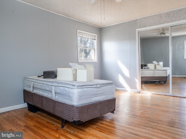 bedroom with baseboards, wood finished floors, a closet, and a textured ceiling