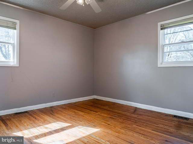 unfurnished room with a wealth of natural light, ornamental molding, and wood finished floors