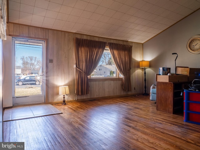 interior space featuring crown molding, wood finished floors, baseboards, and lofted ceiling