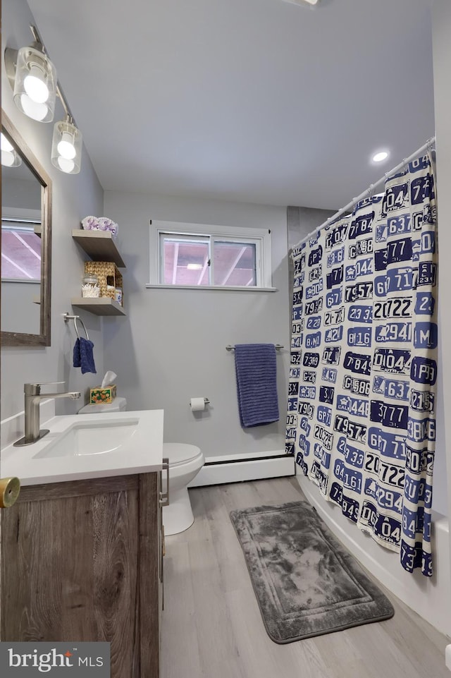 bathroom with curtained shower, toilet, vanity, and a baseboard radiator