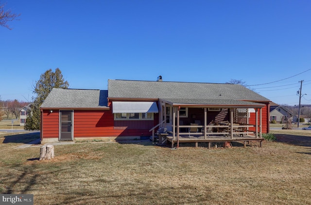 rear view of house with a yard and roof with shingles