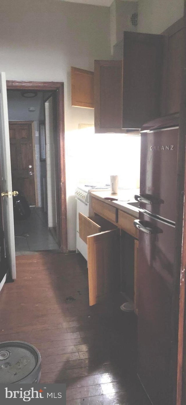 kitchen featuring hardwood / wood-style floors, freestanding refrigerator, and white range with electric stovetop